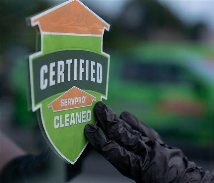 hand from a SERVPRO of Southwest Technician placing a SERVPRO certified clean stick on a commercial building window